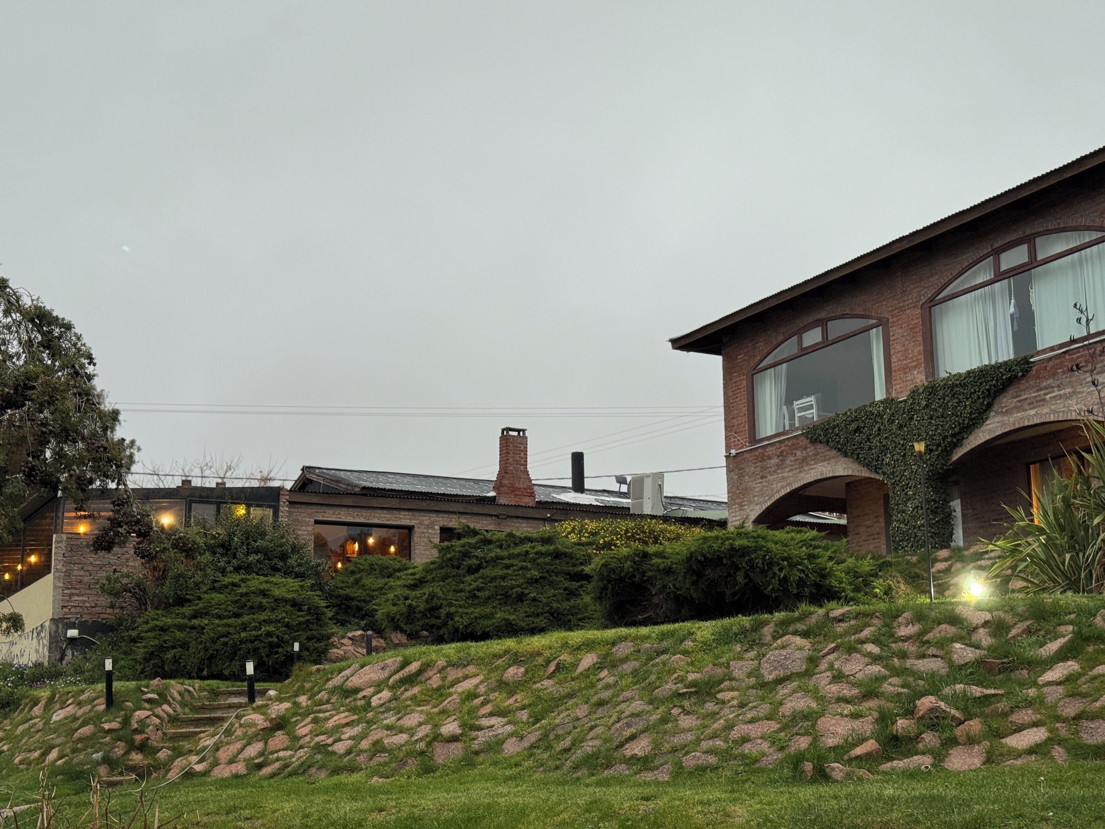 A modern house with a brick exterior, large windows, and a stone pathway leading to the entrance.