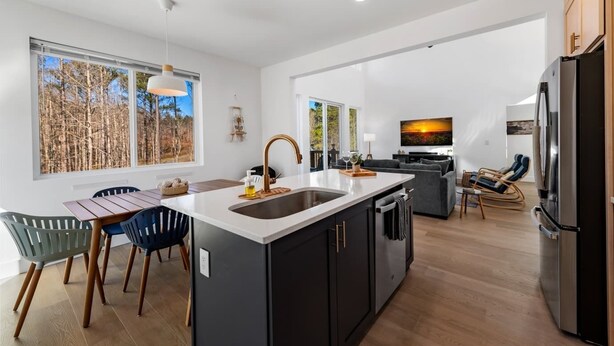 Una cocina moderna con una isla grande, un comedor con sillas, un televisor y una sala de estar con sofá y sillas.