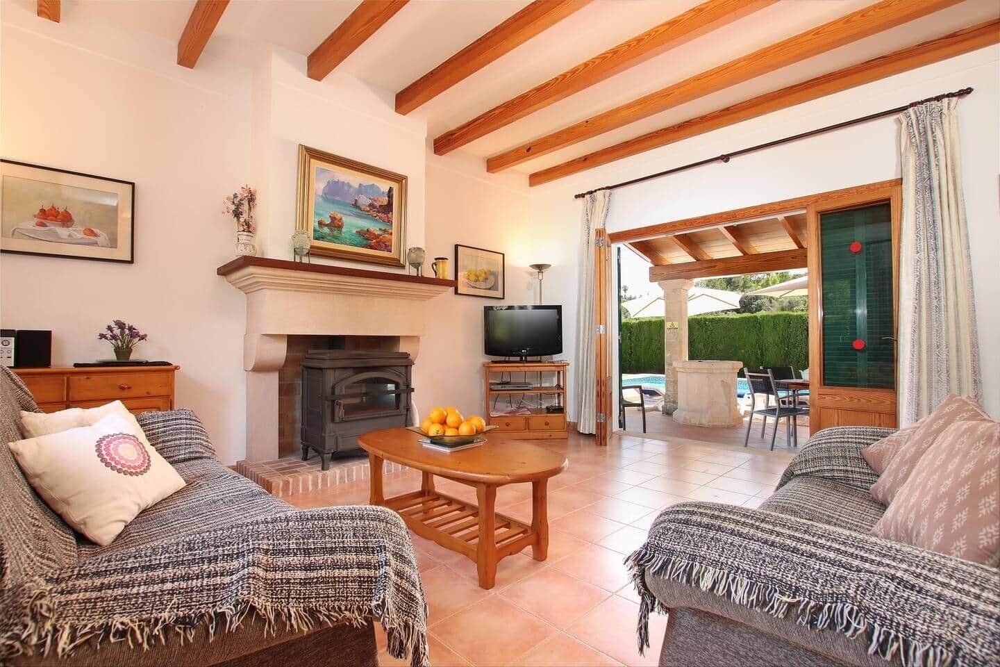 Ein gemütliches Wohnzimmer mit Kamin, Holzbalken und Fernseher.