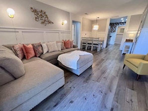 Sala de estar com sofá modular, um banquinho e poltrona amarela.