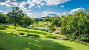 A golf course with a pond, trees, and a clear sky. - Chic Chateau-Less than 2 miles to the strip! (Branson)