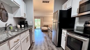 A modern kitchen with white cabinets, stainless steel appliances, and a wooden floor. - Chic Chateau-Less than 2 miles to the strip! (Branson)