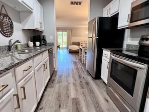Une cuisine moderne avec des meubles blancs, des appareils en acier inoxydable et un plancher en bois.