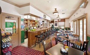 Un restaurante con zona de bar, mesas, sillas y mostrador con menú.