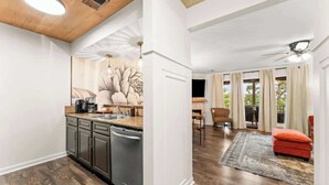 Eine moderne Küche mit integriertem Geschirrspüler, ein Essbereich mit Tisch und Stühlen sowie ein Wohnzimmer mit rotem Sofa und Deckenventilator.
