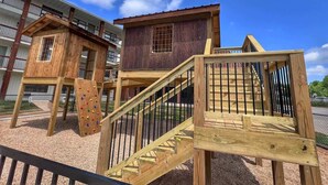A playground with wooden climbing structures and a staircase. - Roark Shores by Branson Landing (Branson)