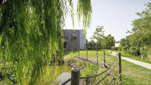 Un espacio exterior tranquilo con un sendero, un pequeño elemento acuático y un edificio de diseño moderno.