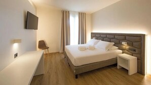 Una habitación de hotel moderna con una cama grande, mesitas de noche, un televisor de pantalla plana y un escritorio.