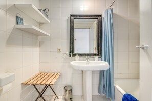 A bathroom with a white sink, mirror, and shower curtain.