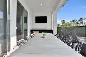 A modern dining area with a long table, chairs, and a TV mounted on the wall.