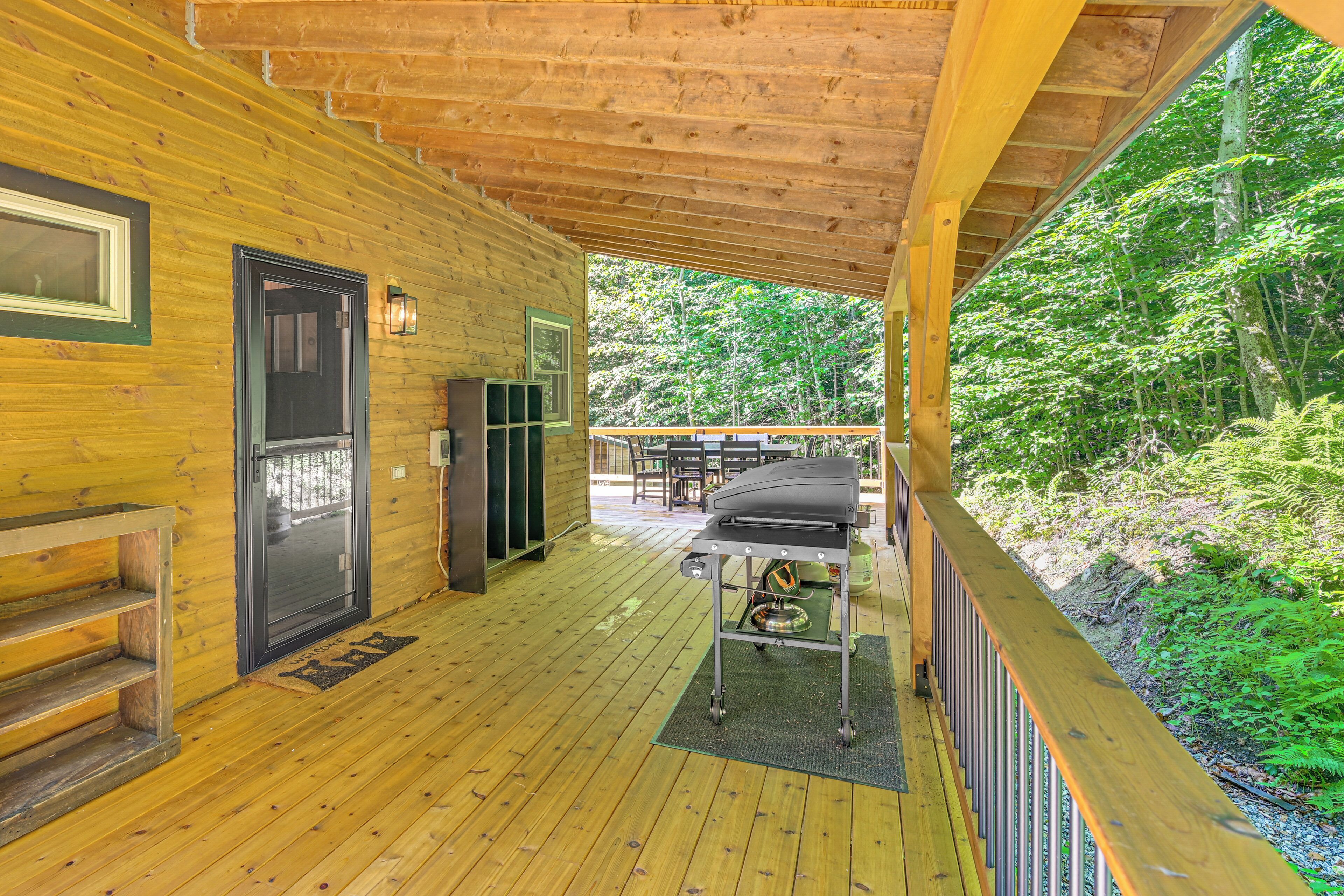 A wooden deck with a grill, a door, and a window.