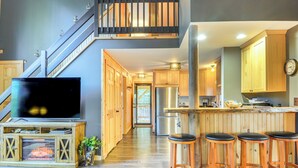 A modern kitchen with wooden cabinets, a stainless steel refrigerator, and a bar area with stools. - Fishing Pond + Pool! Resort Retreat in Wilmington (Wilmington)