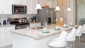 A modern kitchen with white cabinetry, stainless steel appliances, and a granite countertop. - BR Villa w/ Pool, Star Wars Game Room + Resort (Davenport)