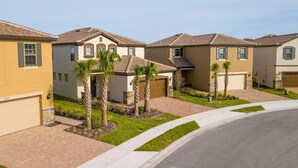 A residential area with houses featuring tiled roofs and stucco walls, surrounded by well-maintained lawns and palm trees. - BR Villa w/ Pool, Star Wars Game Room + Resort (Davenport)