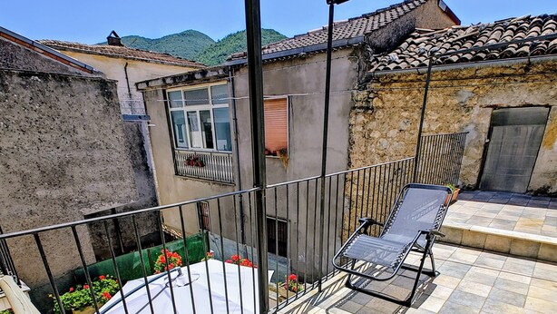 A balcony with two lounge chairs, a small table, and a view of a mountain. - Anna Cerasuolo House | Whole house in mountain hamlet (Molise)