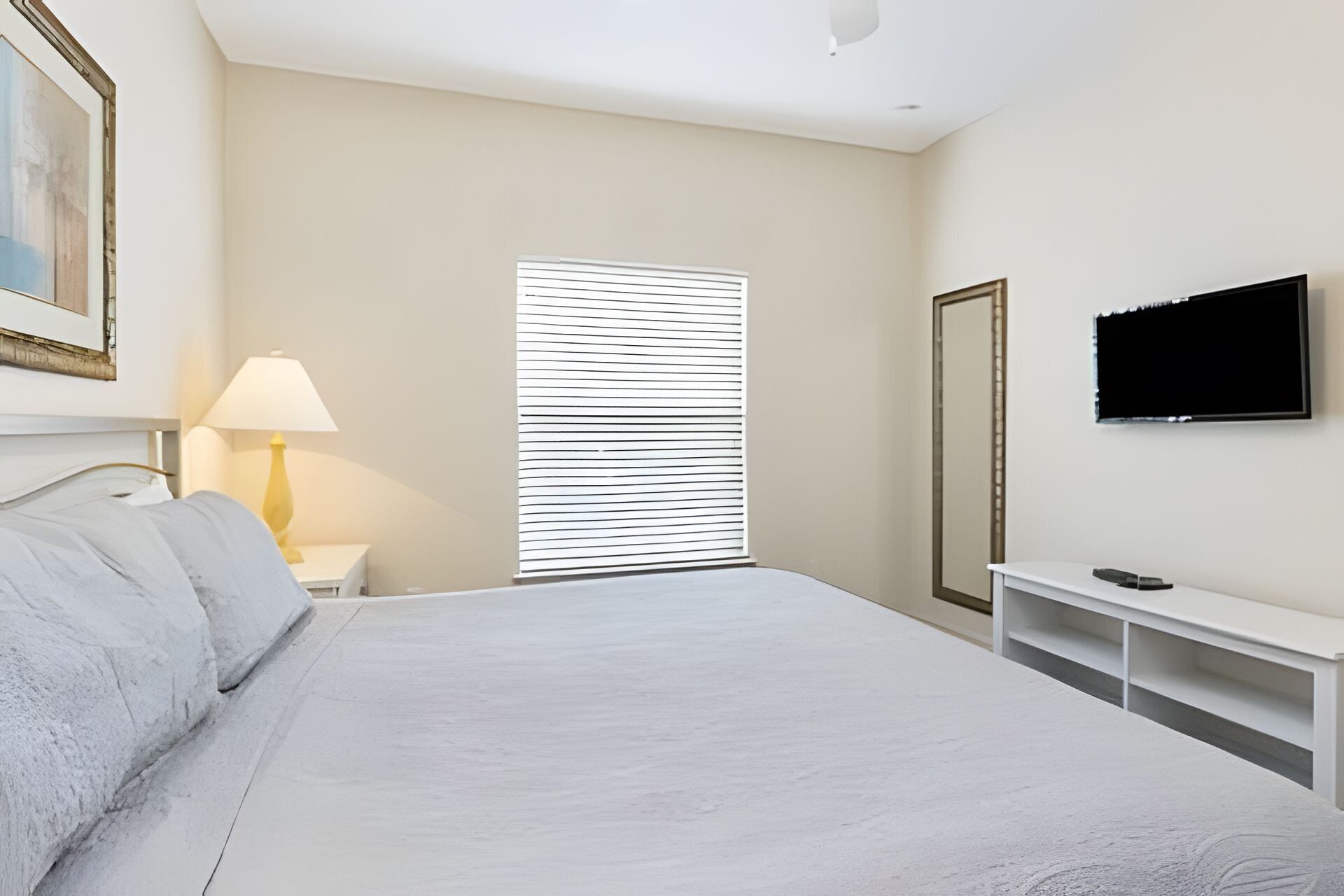 Une chambre d’hôtel équipée d’un lit, d’une télévision, d’un bureau et d’une fenêtre avec des stores.