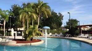 Une piscine avec des chaises longues et un palmier.