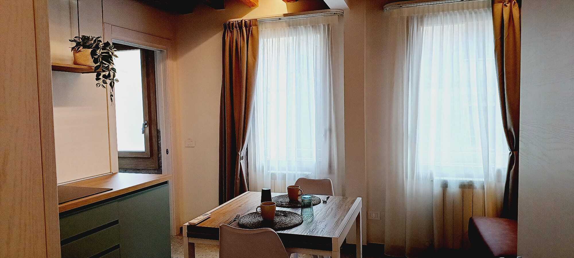 Ein Essbereich mit einem Holztisch, Stühlen und einem Fenster mit Vorhängen.