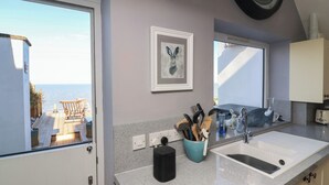 Una cocina con un ventanal grande, un lavabo y un reloj en la pared.