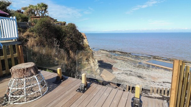 Una terraza de madera con vista al mar, una valla de madera y un tocón de árbol.