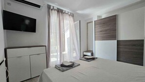 Un dormitorio moderno con cama, televisor, armario y espejo.