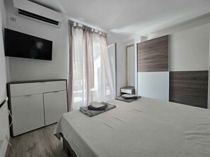 A modern bedroom with a bed, a TV, a wardrobe, and a mirror. - Holiday apartment Flat with balcony near the beach (Njivice)