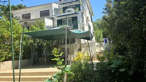 Un edificio de dos pisos con balcón, antena parabólica y toldo verde.