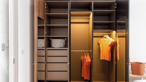 A walk-in closet with open shelves, a hanging rod, and a mirrored closet door. - The Marlo (London)
