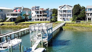 A waterfront property with a dock, a boat, and a pier leading to a house with multiple balconies. - The Channel House~Water Views~Dock + Boatslip~Walk to beach! (Wrightsville Beach)