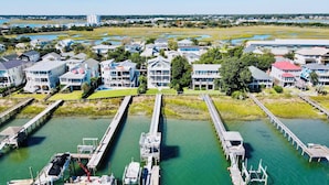 An aerial view of a waterfront property with multiple docks, a marina, and residential buildings. - The Channel House~Water Views~Dock + Boatslip~Walk to beach! (Wrightsville Beach)