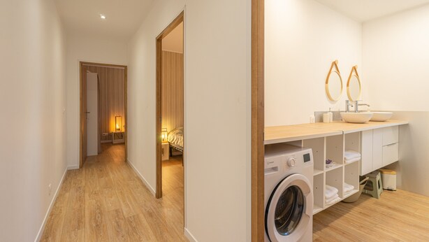 Een moderne badkamer met een wasmachine, een wastafel en een spiegel.