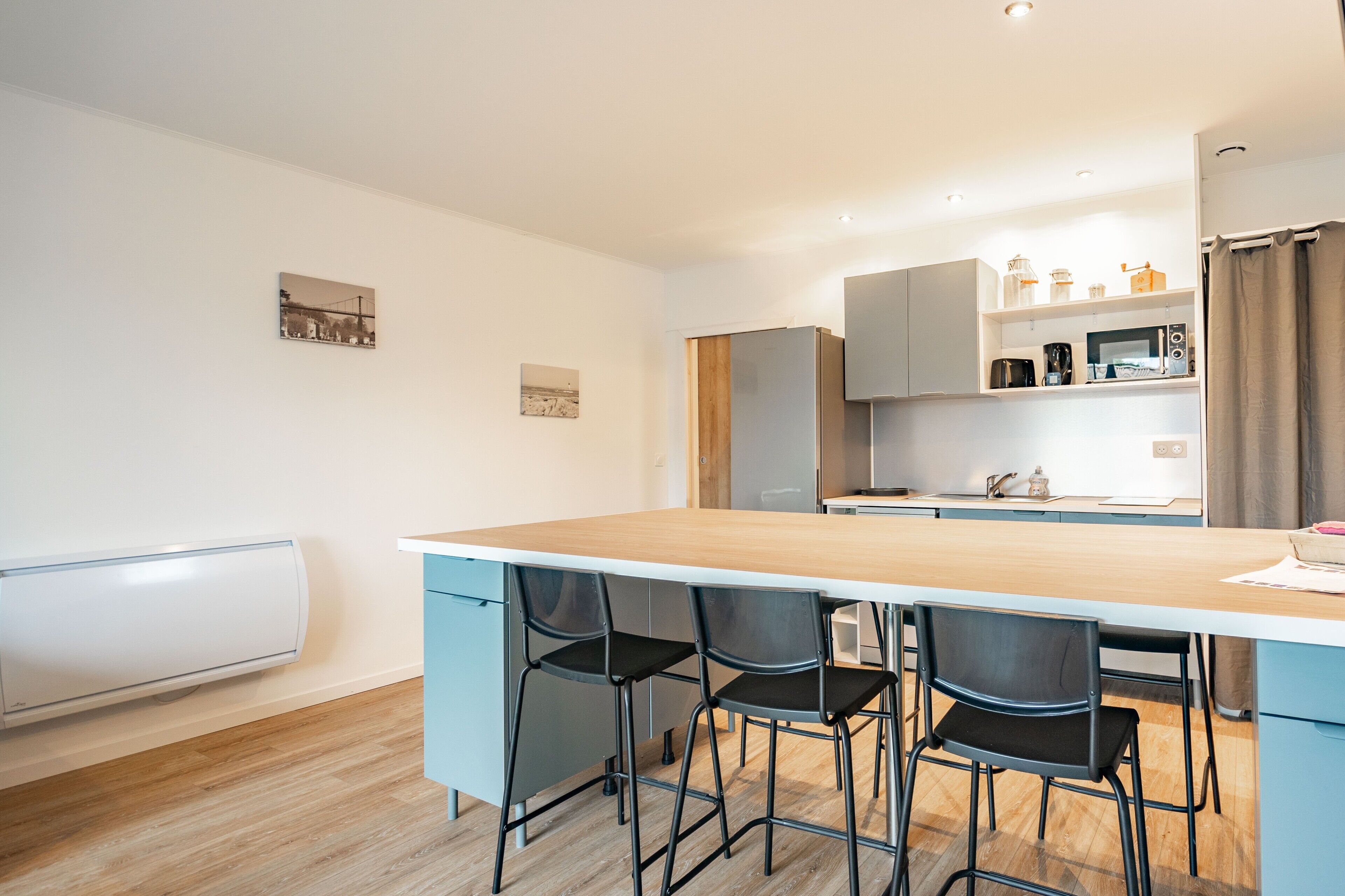 Een moderne keuken met een houten kookeiland, zwarte stoelen en een wit aanrecht.