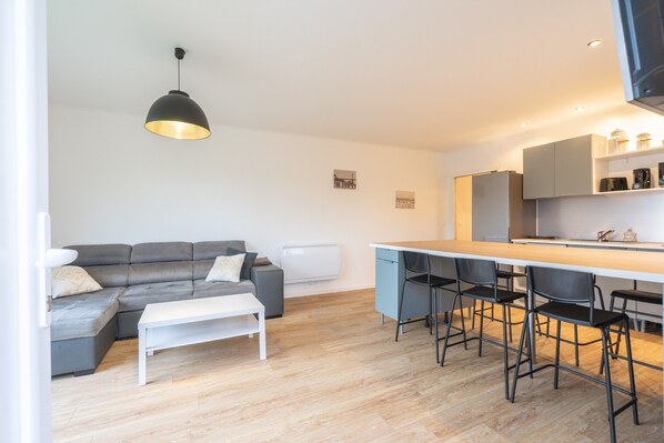 Un salon moderne avec un canapé gris, une table basse blanche et une suspension noire.