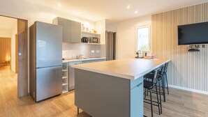 Een moderne keuken met een centraal eiland, een ingebouwde magnetron en een flatscreen televisie aan de muur.