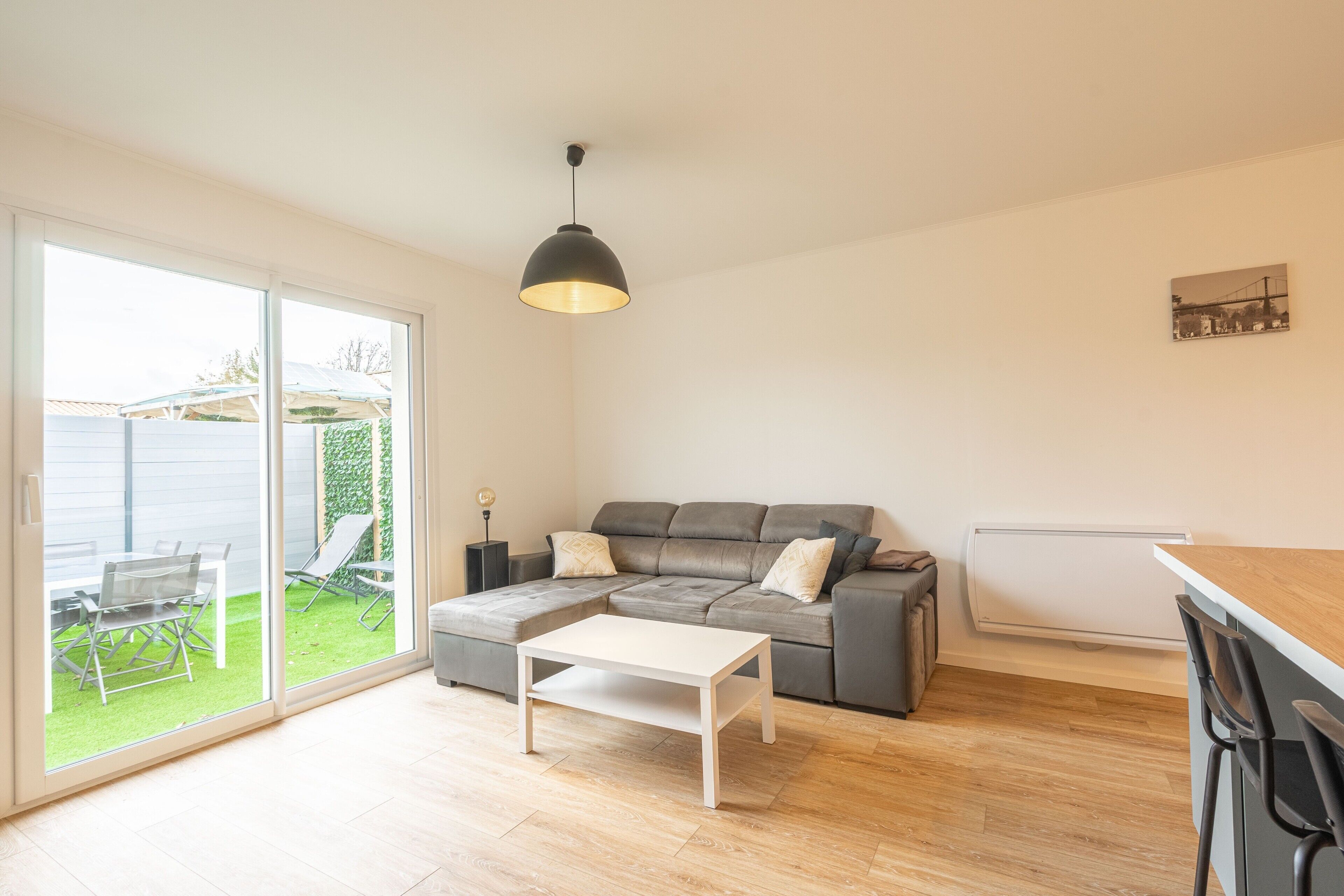 A modern living room with a grey sectional sofa, a white coffee table, and a black pendant light.