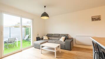 A modern living room with a grey sectional sofa, a white coffee table, and a black pendant light.