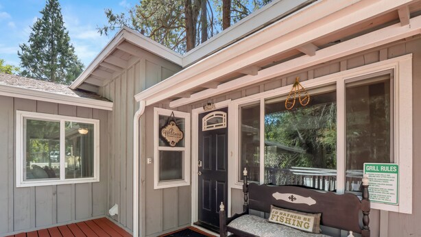 A wooden building with a porch, a welcome sign, a bench, and a sign listing grill rules. - 25 min to Yosemite - BBQ - Hot Tub -  Private Creek (Oakhurst)