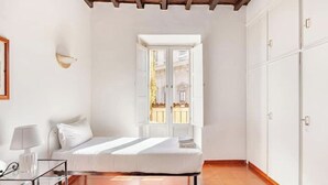 A bedroom with a bed, a bedside table, a lamp, a window, and a wardrobe. - Campo 8 - Spacious Apartment with View of Campo dè Fiori (Roma)