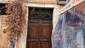 A building with a large wooden door, a potted plant, and a sign with "ROMO" on it.