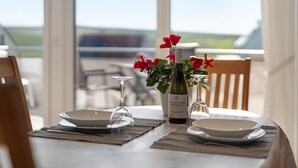 Ett matbord med en vinflaska, ett vinglas och en skål, placerat på en duk.
