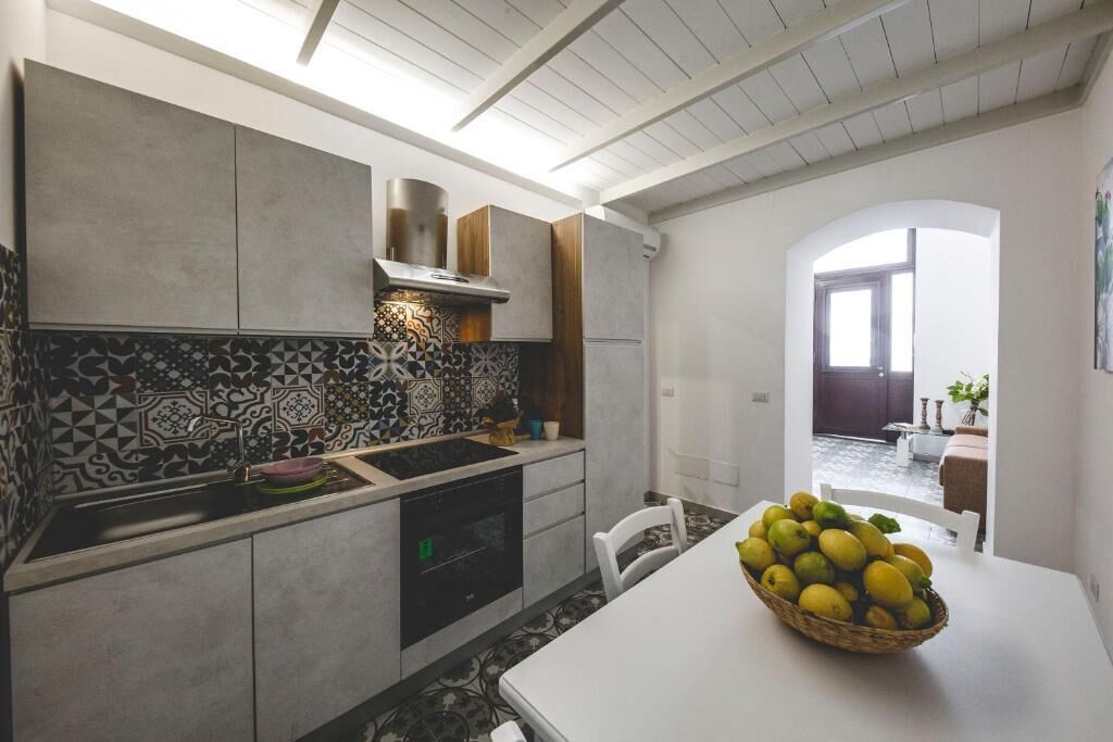Uma cozinha moderna com painel decorativo, forno embutido e área de refeições com mesa e cadeiras.