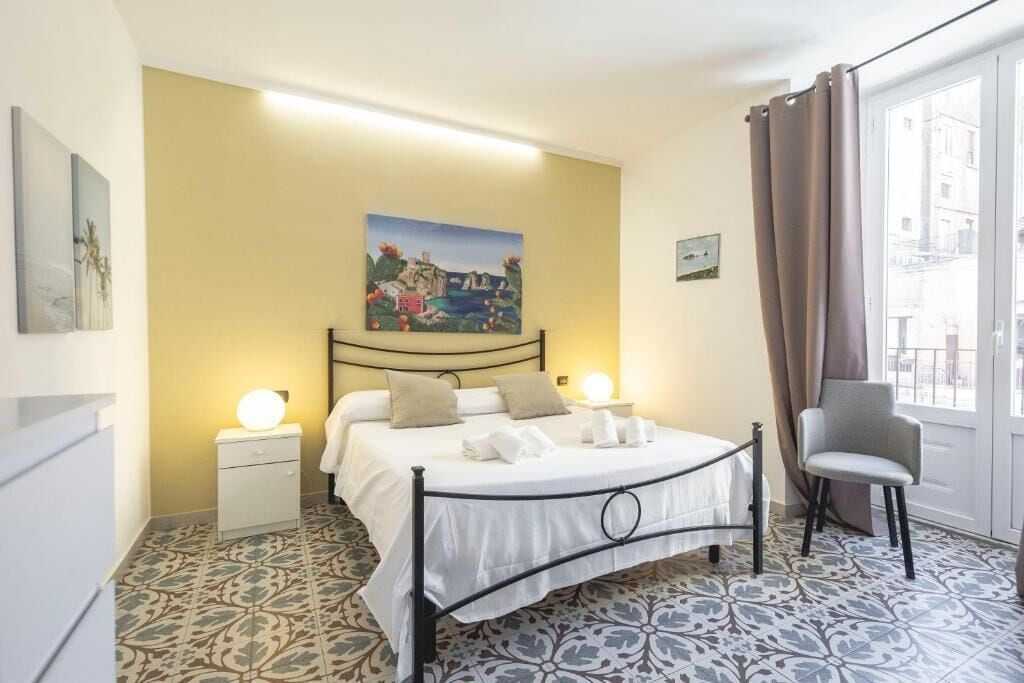 A bedroom with a bed, bedside tables, a chair, and a painting on the wall.