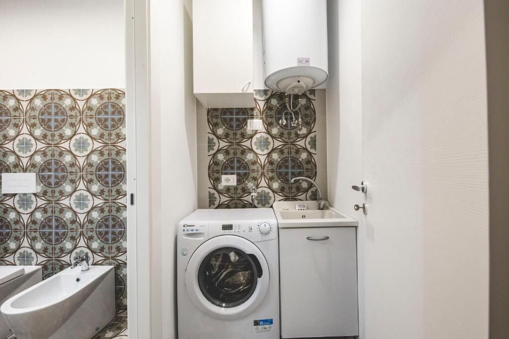 A compact bathroom with a washing machine, a sink, and a bathtub.