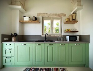 A kitchen with green cabinets, a sink, a window, and a microwave. - Charming Trulli & Lamie in Locorotondo • 2 BR • 2 BA (1 Ensuite) • Patio (Puglia)