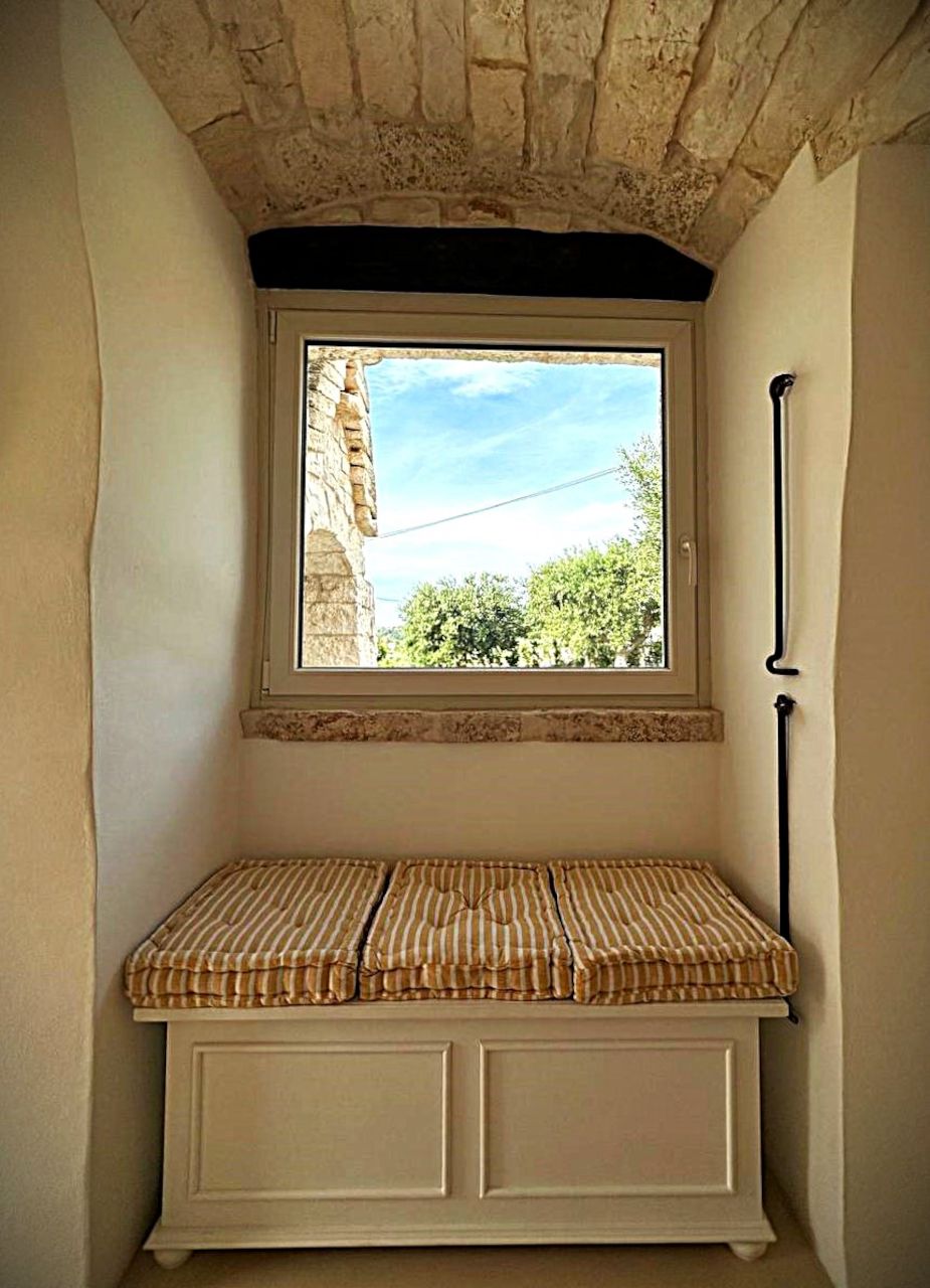 Ein kleines Fenster mit Blick auf Grünflächen und einen Steingebäudes.