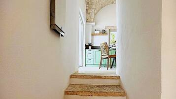 A staircase leading to a kitchen area with green cabinets and a chair.