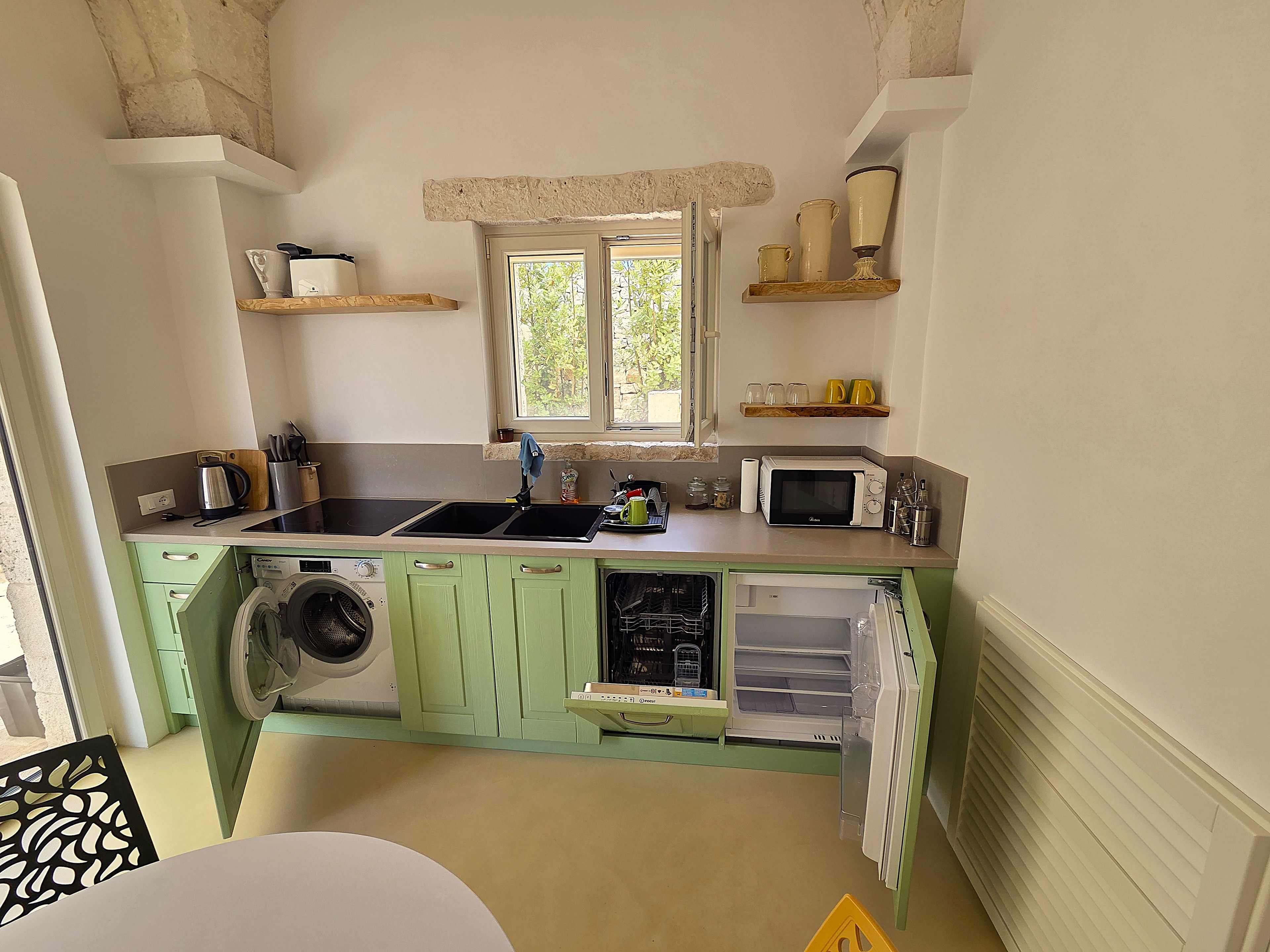 A compact kitchen with a washing machine, a microwave, and a sink.
