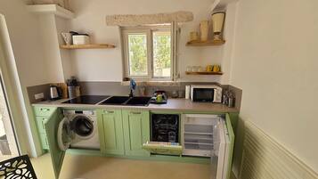 A compact kitchen with a washing machine, a microwave, and a sink.