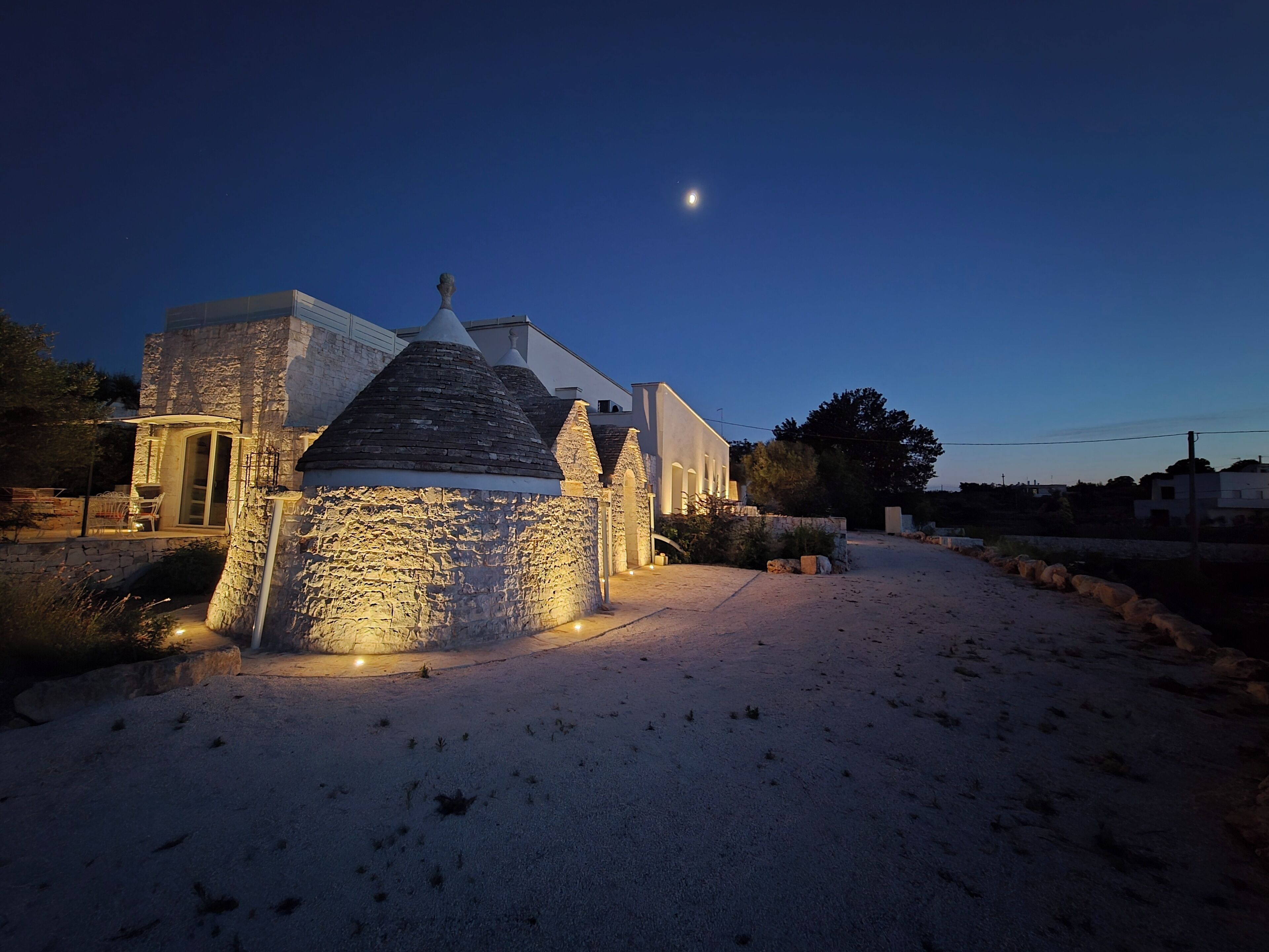 A stone building with a modern extension, a paved area, and a clear night sky.