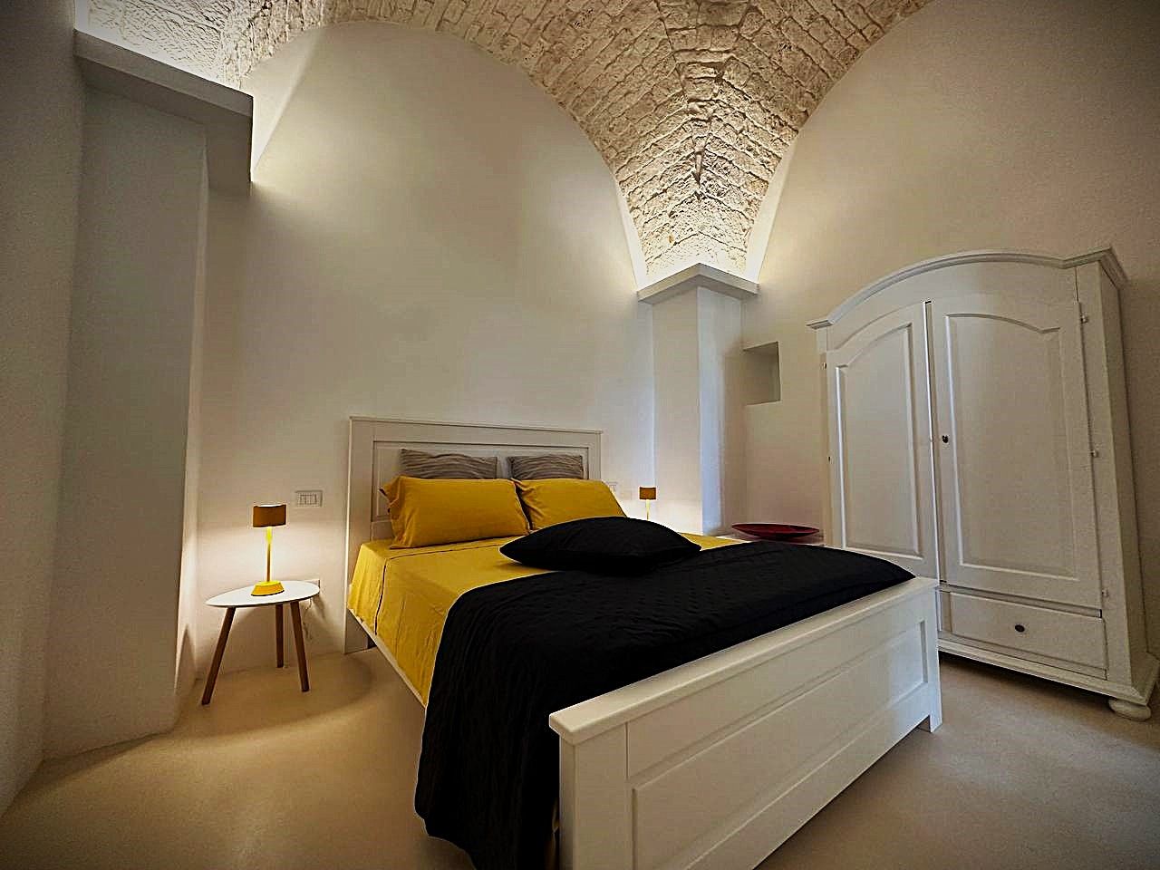 Ein Schlafzimmer mit einem Bett, Nachttischen, einem Kleiderschrank und einer dekorativen Decke.